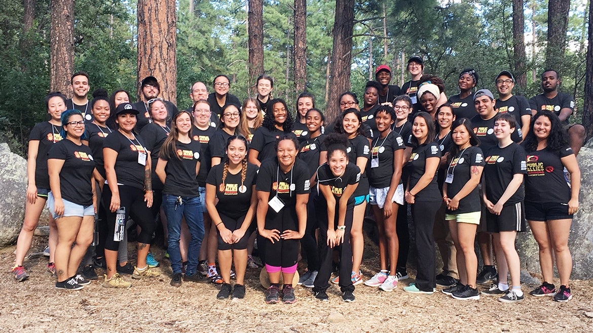 A group of people smile while surrounded by forest.