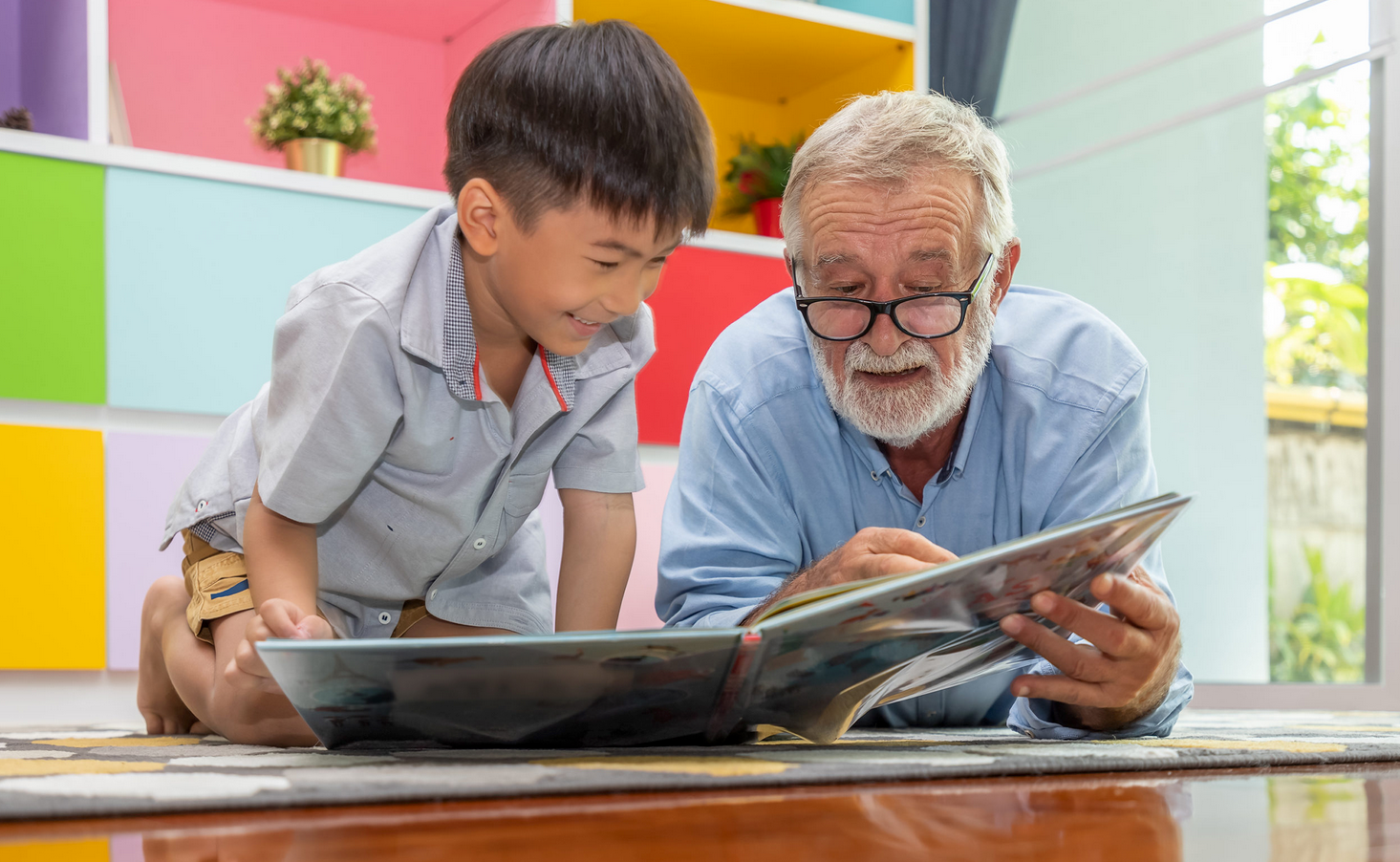 A senior citizen and child read a book together.