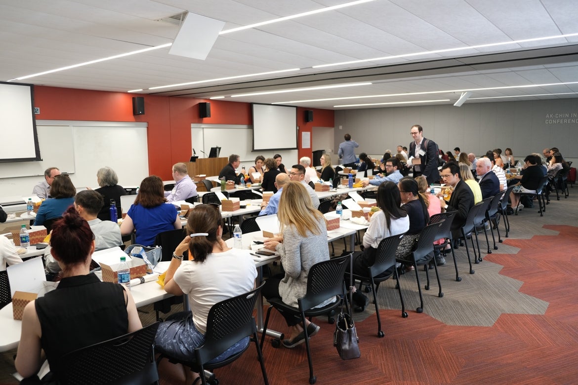 Inside an auditorium, Robert Ashcraft, the executive director of the ASU Lodestar Center and the 2019 conference chair, stands on a stage giving a powerpoint presentation to an audience sitting at several circular tables. The powerpoint slide reads "2019 West Coast Nonprofit Data Conference, Welcome".