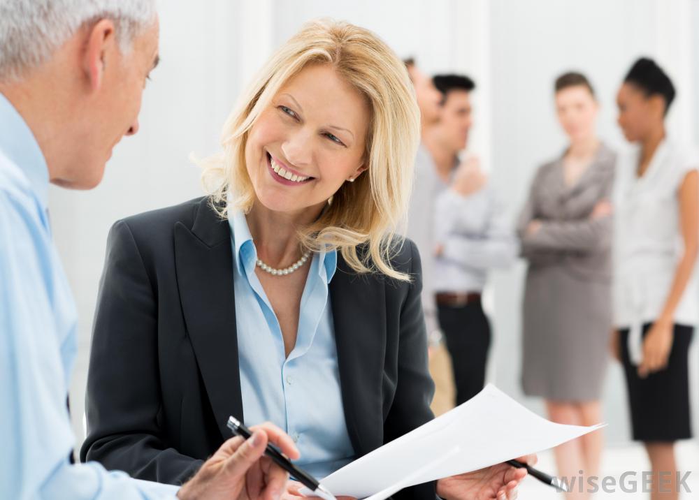 2 people smile and discuss while others in the background group together.