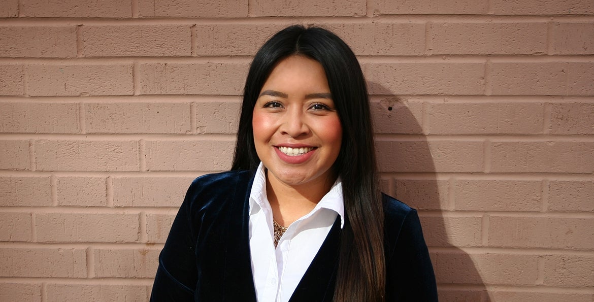 Fernanda Torres Maqueda smiles. Behind her is a brick wall.