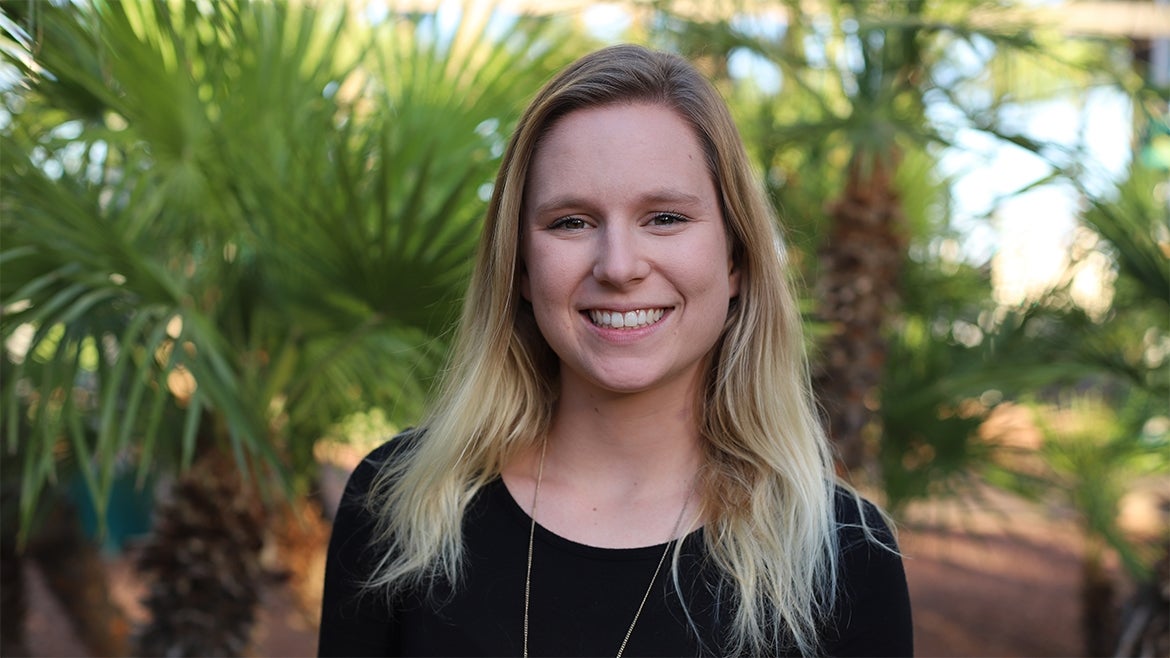 McKeena Rodham smiles. Behind her are palm trees.