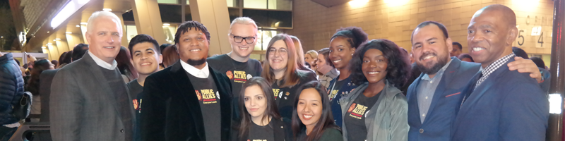 Standing outside a building a night, Public Allies members and ASU faculty smiel.