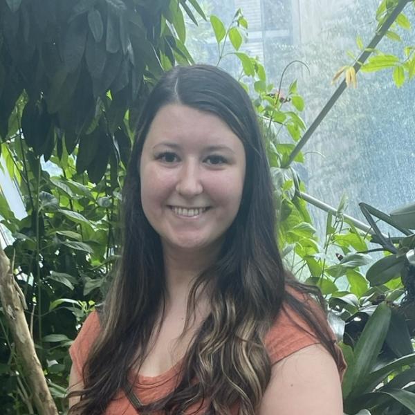 Woman smiling while standing in front of multiple plants